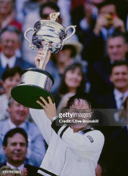 Martina Hingis of Switzerland holds the Daphne Akhurst Memorial Cup aloft after defeating Conchita Martínez of Spain in the Women's Singles Final...