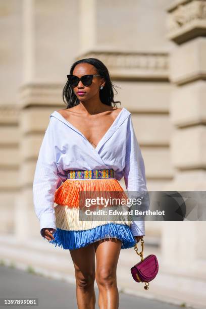 Emilie Joseph @in_fashionwetrust wears black sunglasses, silver and blue stone earrings, a white striped print pattern V-neck / oversized /...