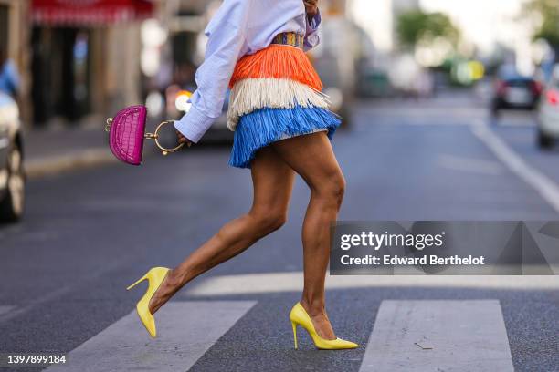 Emilie Joseph @in_fashionwetrust wears a blue / white / orange fringed made from natural raffia by Stella Jean for Desigual, a neon pink shiny...