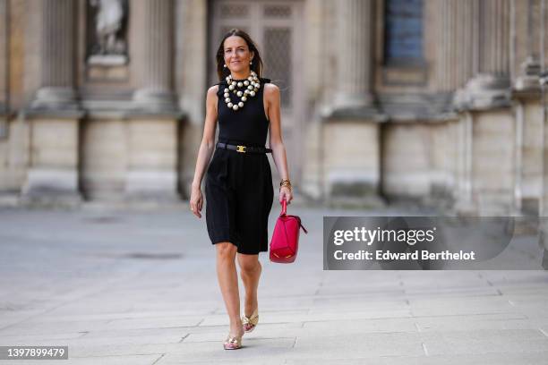 Alba Garavito Torre wears white pearl pendant earrings, an oversized white pearls necklace, a black halter neck tank-top / body from Surprise Paris,...