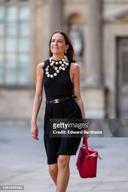 Alba Garavito Torre wears white pearl pendant earrings, an oversized white pearls necklace, a black halter neck tank-top / body from Surprise Paris,...