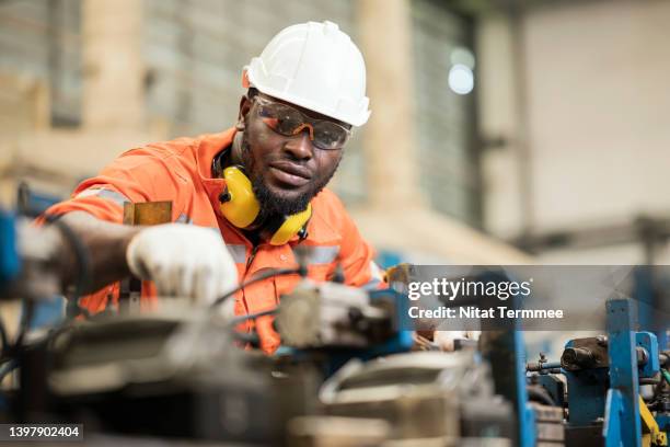 welding quality assurance & quality control processes procedure in automobile industry.  male african american engineer is working in a welding production line while adjusting the accuracy of welding assembly jig auto parts in a industry shop floor. - manufacturing occupation bildbanksfoton och bilder