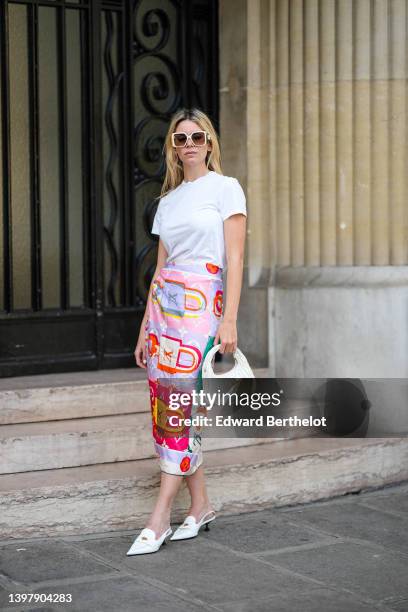 Natalia Verza wears white sunglasses from Louis Vuitton, a white t-shirt, a multicolored silk print pattern scarf as a midi skirt from Louis Vuitton,...