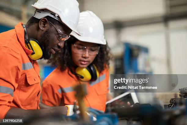 boosting and improving manufacturing process efficiency in welding assembly line. african american manufacturing process engineers team having discussion on welding jig assembly to tolerance variations in the product parts. - robotics alive stock pictures, royalty-free photos & images