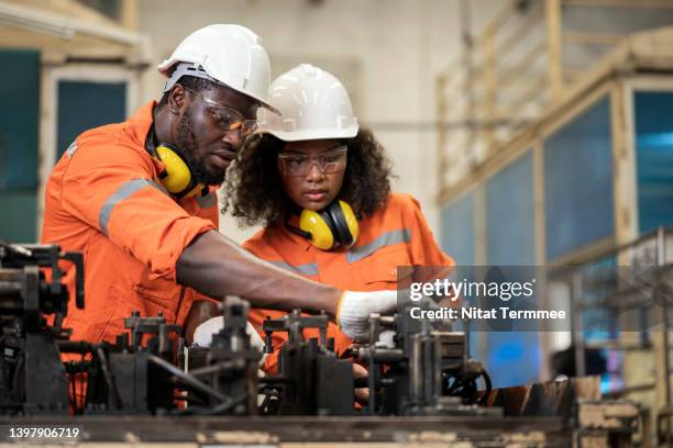 process safety for every operation in welding assembly of an auto parts manufacturing industry. male and female african american engineers having a discussion about welding assembly process base on safety standard in a production line. - work gender equality stock-fotos und bilder
