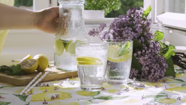 Pouring soda water with lemon slices into a glass