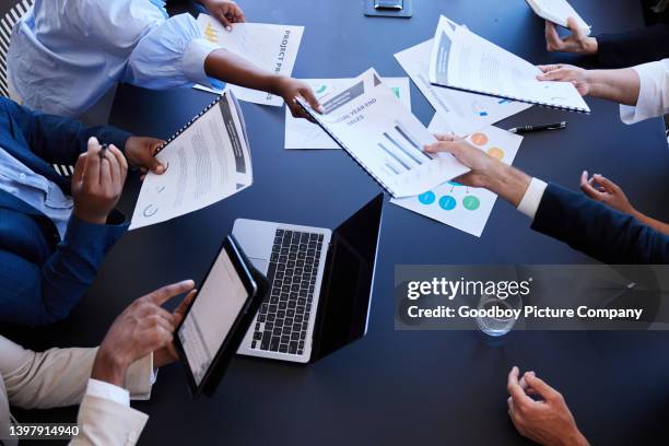 businesspeople passing around graphs and charts during an office meeting - planned giving stock pictures, royalty-free photos & images