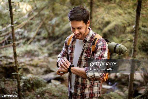 hiker checking his smart watch in the forest - wearable computer bildbanksfoton och bilder