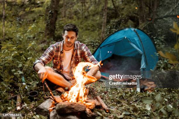 hiker setting up bonfire in his camp - hysa bildbanksfoton och bilder