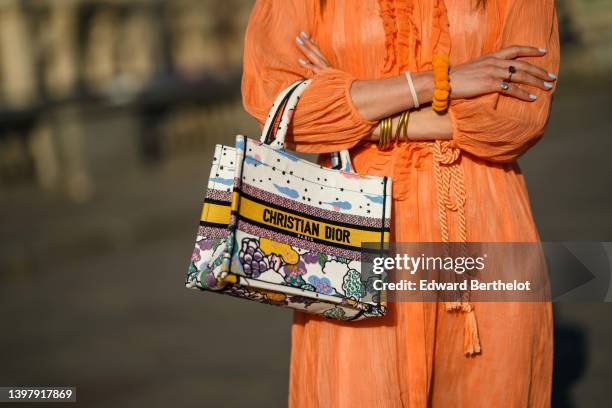 Zita d'Hauteville wears an orange ruffled / ribbed / long puffy sleeves / belted midi dress, an oversized yellow bracelet, gold rings, a white with...