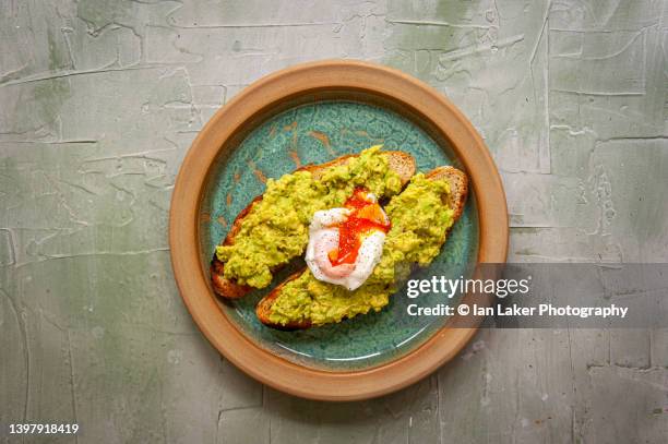 littlebourne, kent, england, uk. 11 may 2022. avacado and poached egg on toast. - escalfado fotografías e imágenes de stock