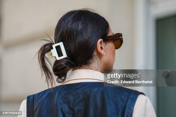 Gabriella Berdugo wears a white hair clip, black sunglasses, gold and silver pendant necklaces, a black shoulder-off / cropped top, a black shiny...