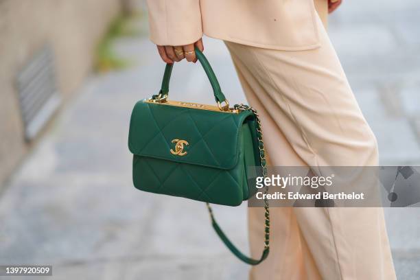 Gabriella Berdugo wears a beige oversized blazer jacket, matching beige high waist flared pants, a green shiny leather Trendy handbag from Chanel,...