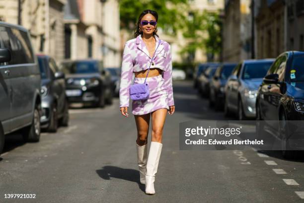 Patricia Gloria Contreras wears purple sunglasses from Balanciaga, gold logo earrings from Louis Vuitton, a pale purple and white print pattern...