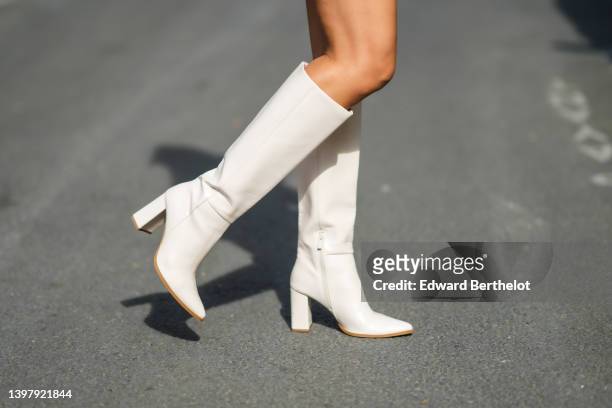 Patricia Gloria Contreras wears white latte leather block heels / pointed / knees boots, during a street style fashion photo session, on May 10, 2022...