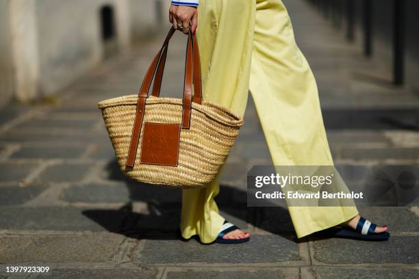 Gabriella Berdugo wears yellow wide legs pants, a beige wickers and brown shiny leather basket bag from Loewe, navy blue and white strap sandals from...