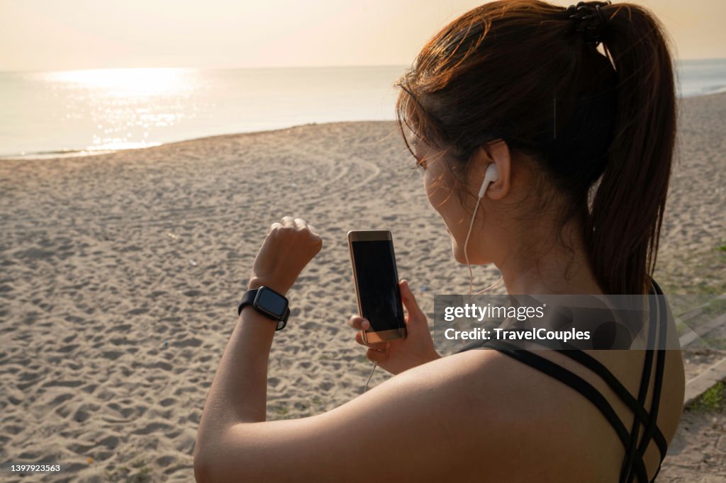 Women setting up the fitness smart watch for running. Young fitness women runner checking time from smart watch. Young woman checking heart rate while jogging in the park.