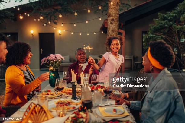 big family garden party celebration, gathered together at the dining table outdoors - african at dining table stockfoto's en -beelden
