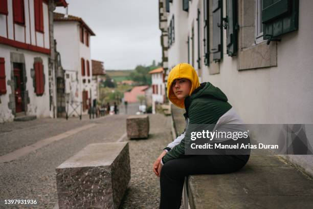 boy dressed in casual clothes, sitting on a street in a french village - espelette france imagens e fotografias de stock