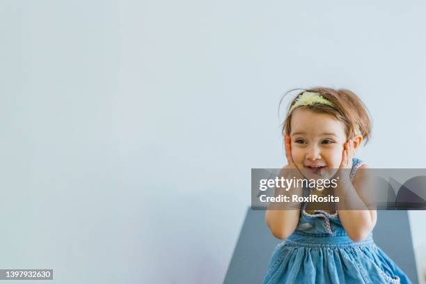 little girl smiling grabbing her face with both hands in surprise - argentina girls stock pictures, royalty-free photos & images