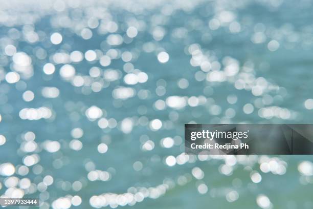 blurred background with bokeh depicting glare on the water at the sea or lake. - water surface line stock pictures, royalty-free photos & images