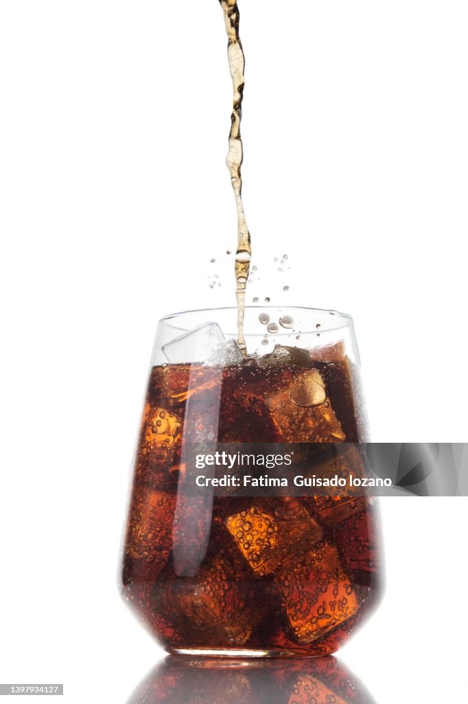 Glass of cola with ice and soft drink is being poured into the glass.