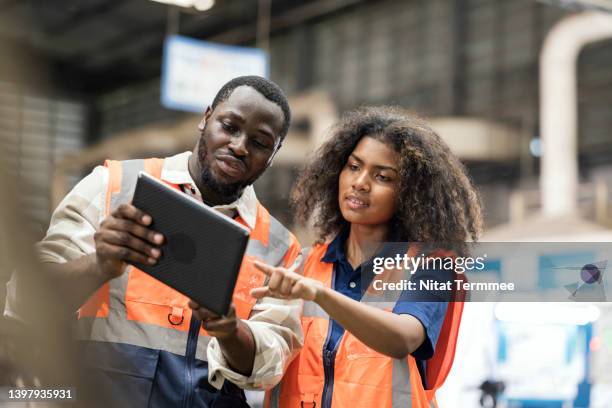 real-time production information increasingly important for manufacturers industry. african american production control engineers is having discussion on production daily report for resource planning related to production in factory shop floor. - global solutions stockfoto's en -beelden