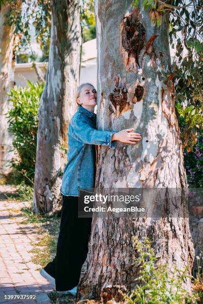 charming blonde woman hugging old tree trunk - respect nature stock pictures, royalty-free photos & images