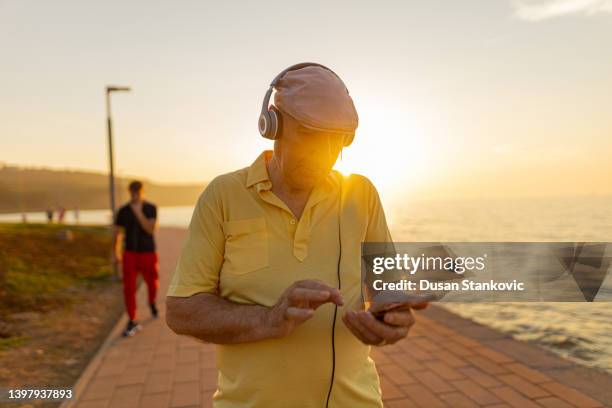 hombre mayor caminando por la calle y escuchando música - vida sencilla fotografías e imágenes de stock