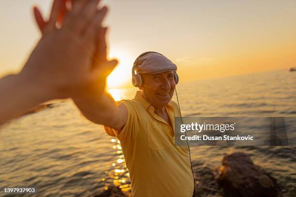 hombre mayor sonriente sosteniendo la mano de alguien - vida sencilla fotografías e imágenes de stock