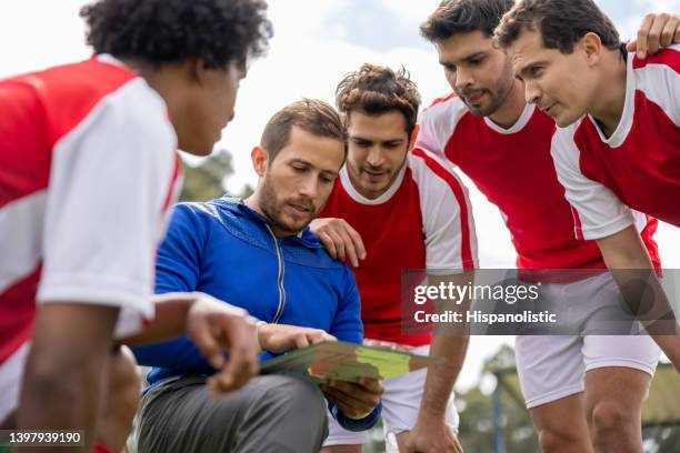 soccer coach talking to his team about their strategy for the game - treinador desportivo imagens e fotografias de stock