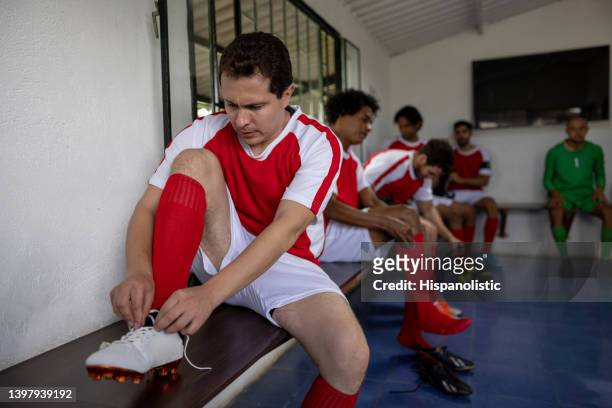 soccer player fixing his soccer shoes in the dressing room - lace shirt stock pictures, royalty-free photos & images