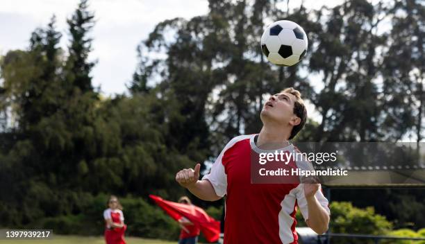 joueur de football menant le ballon sur le terrain - heading the ball photos et images de collection