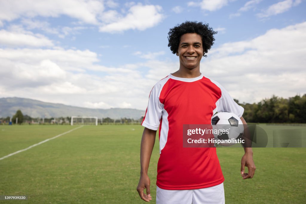 Happy soccer player holding a soccer ball and smiling