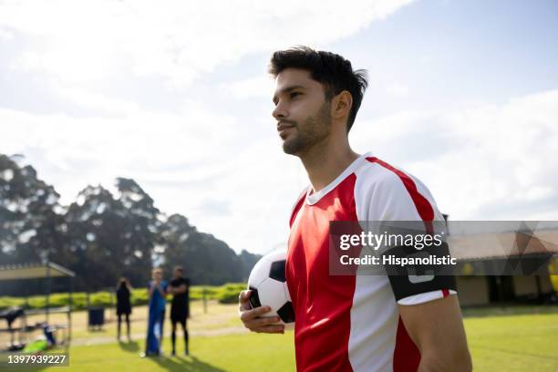 soccer player wearing a captain band and holding a soccer ball in the field - skipper stockfoto's en -beelden