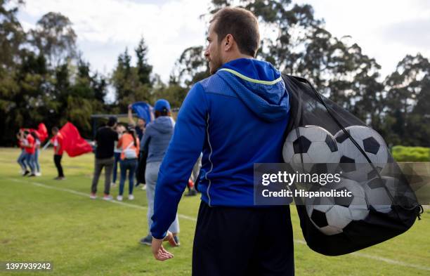 coach carrying a mesh bag with soccer balls at the end of the practice - sports equipment stock pictures, royalty-free photos & images
