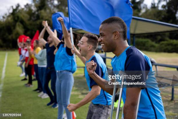 injured soccer player with a group of soccer fans cheering for their team at the field - crutches stock pictures, royalty-free photos & images
