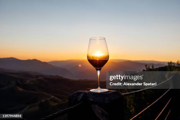 glass of red wine against sunset sunset in the mountains - weinglas stock-fotos und bilder