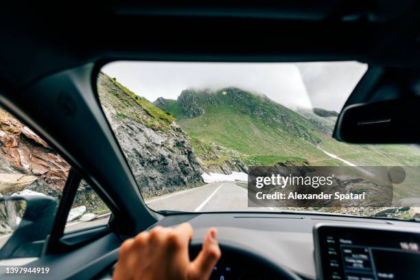 man driving on a mountain road among rocks and snow, personal perspective view - voiture conducteur photos et images de collection