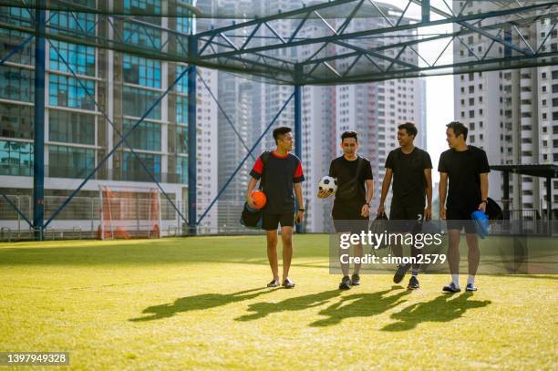 smiling asian male footballers walking onto sports field for practice - asian team sport stock pictures, royalty-free photos & images