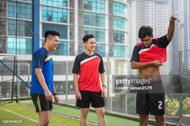 glückliche junge asiatische männerfußballmannschaft, die das sporttrikot für das morgendliche training vorbereitet. - get dressed male stock-fotos und bilder