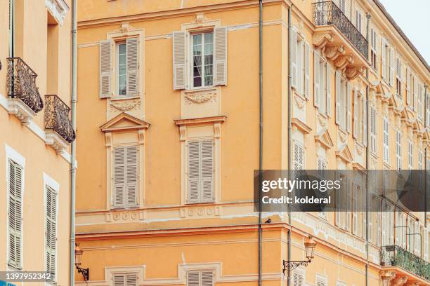 orange walls of beautiful elegant old apartment buildings with white jalousie windows , cannes, provence, france - cannes building stock pictures, royalty-free photos & images