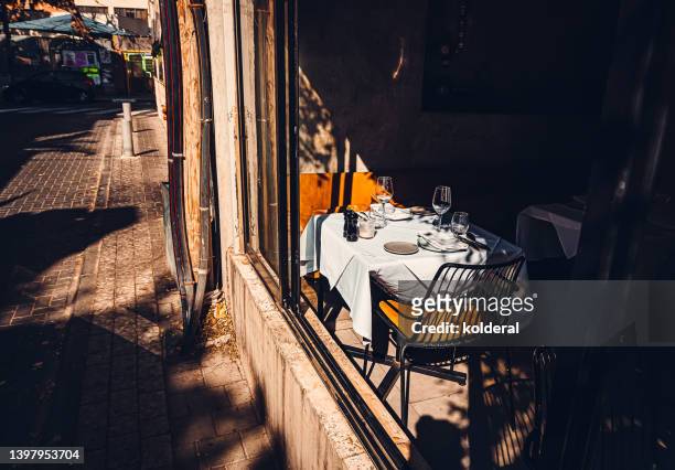 unoccupied restraunt table setting with white flatware, plates and wine glasses at sunset light and shadow - luxury table setting stock pictures, royalty-free photos & images