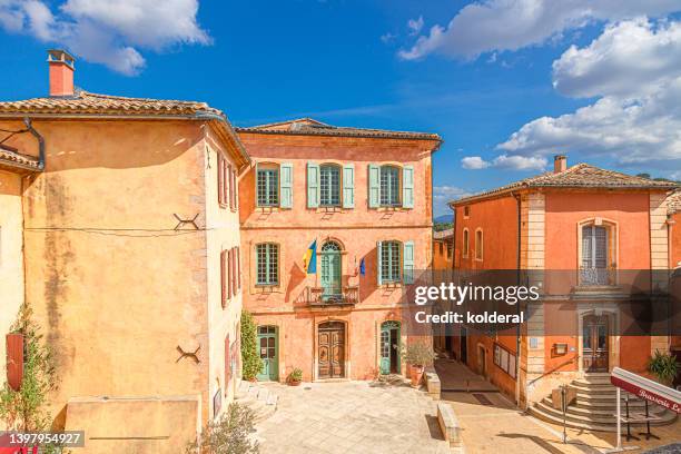 traditional mediterranean architecture of picturesque village of roussillon. ochre tones colored walls of historic residential buildings against blue sky - vaucluse stock-fotos und bilder