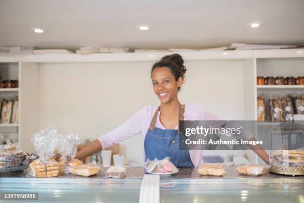potrait of happy female afro-american entrepreneur  at counter displaying sweet pastries at patisserie - alfajores stock pictures, royalty-free photos & images