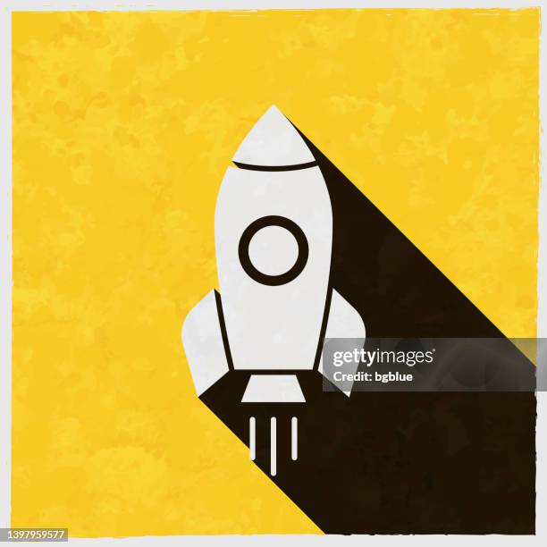 rocket. icon with long shadow on textured yellow background - rocket launch fire stock illustrations