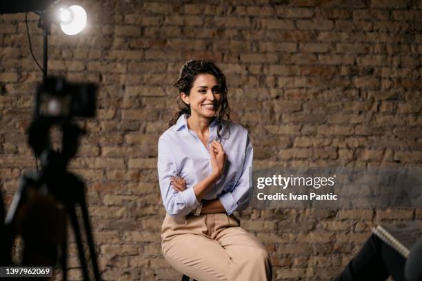 young woman giving an interview in a studio - behind the scenes interview stock pictures, royalty-free photos & images