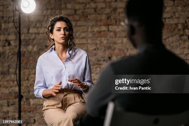 junge frau gibt ein interview in einem studio - interview gespräch stock-fotos und bilder