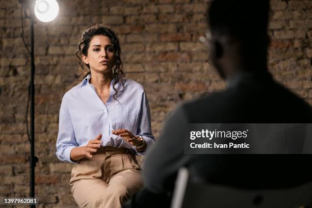 young woman giving an interview in a studio - media interview stockfoto's en -beelden