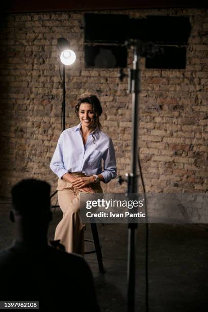 attractive woman giving an interview in a modest studio - fame press stock pictures, royalty-free photos & images